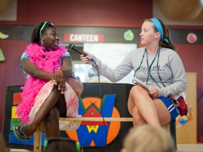 Staff member extends a microphone to a camper.